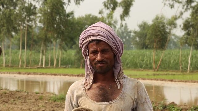 Portrait of a rural Indian farmer standing in agricultural field, showing hardworking lifestyle, traditional attire, and authentic village environment.