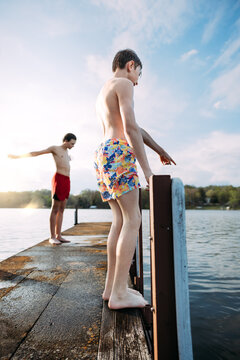 Preteen boys standing on lakeside dock in summer