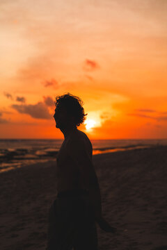 Man silhouette against glowing orange sunset on beach, Nyang Nyang