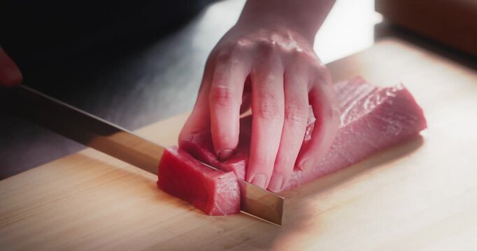 包丁で生のマグロの刺身を切り分ける寿司職人の手元　和食・日本料理のクローズアップ　魚介・海鮮料理　旅行・観光