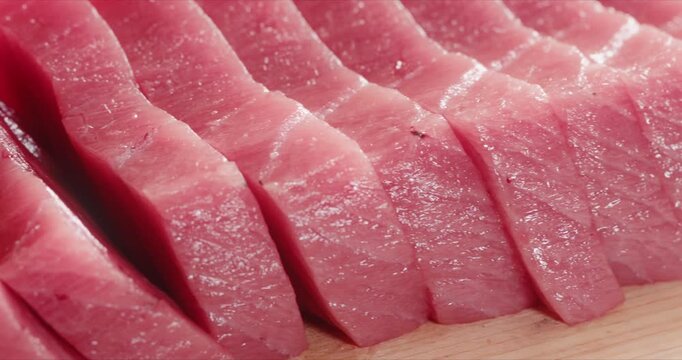 包丁で生のマグロの刺身を切り分ける寿司職人の手元　和食・日本料理のクローズアップ　魚介・海鮮料理　旅行・観光