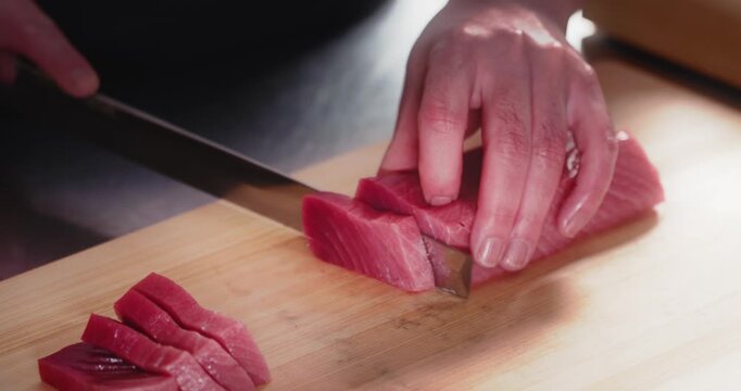 包丁で生のマグロの刺身を切り分ける寿司職人の手元　和食・日本料理のクローズアップ　魚介・海鮮料理　旅行・観光