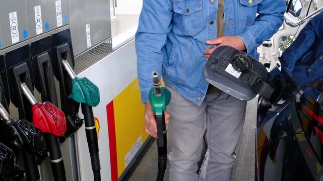 Mid Shot of Unrecognizable Man Hands Taking Fuel Nozzle and Inserting Into Car Tank at Gas Station, Preparing Vehicle for Refueling During Rising Fuel Prices and Economic Pressure.