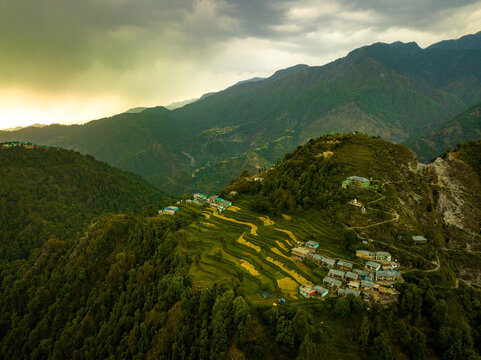terraced farming village in mountain landscape
aerial view of hillside agriculture settlement
remote mountain village with terrace fields
drone shot of rural hillside farming india
scenic mountain vil