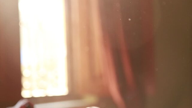 Soft morning sunlight streaming through a window illuminating floating dust particles, creating a warm, peaceful, and atmospheric indoor scene.