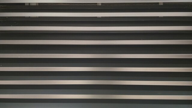 Metallic grey siding texture. Horizontal metal louver wall texture. Modern horizontal metal louver or siding with consistent parallel lines. 