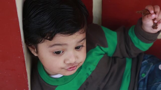 Adorable young girl sitting indoors with playful expression, capturing innocent childhood, curiosity, and natural candid moment in a home environment.