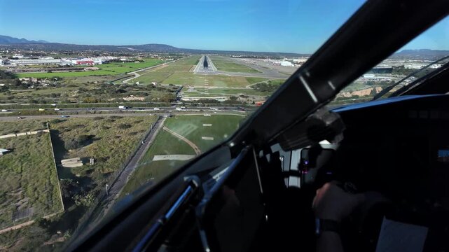 An immersive cockpit view, with the view of Captain hand flying manually a jet airplane during the final approach to Palma de Mallorca Airport runway under a blue sky.
