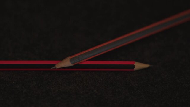 Detailed View of Crossed Red and Orange Pencils on Dark Fabric