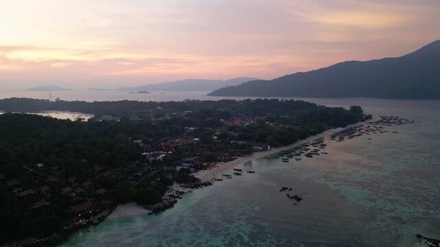 Koh Lipe, Thailand: Aerial drone footage of dramatic sunset over Koh Lipe, an island in Andaman sea of Thailand. Taken with upward and tilt down motion showing long tail boats by the beach
