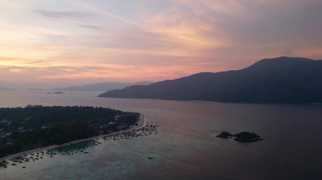 Koh Lipe, Thailand: Aerial drone footage of dramatic sunset over Koh Lipe, an island in Andaman sea of Thailand. Taken with forward motion showing long tail boats along the famous sunrise beach