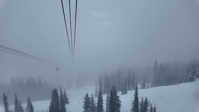 Heavy snow and fog in the backcountry of Whistler; Aerial POV riding the PEAK 2 PEAK gondola connecting Whistler Blackcomb Mountain to Whistler Mountain Ski Resort.