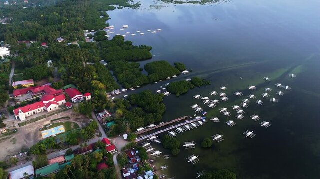 hot of the lush coastline and rural settlements of Panglao Island, Bohol. Cinematic drone flight over tropical forests and coastal villages in the Philippines
