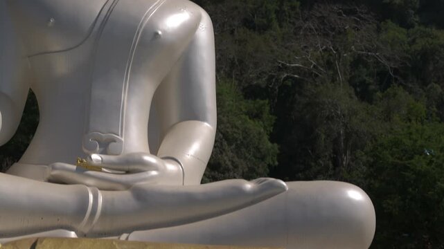 Tilt up reveal from a golden dharma wheel to a pearl Buddha with karst mountains behind.