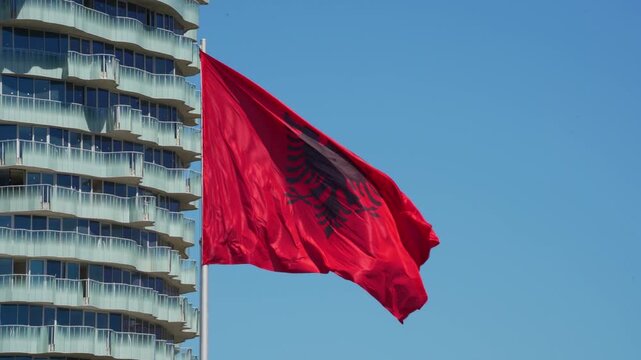 Albanian Flag Waving Against Modern Architecture Background in Central Square of Tirana City