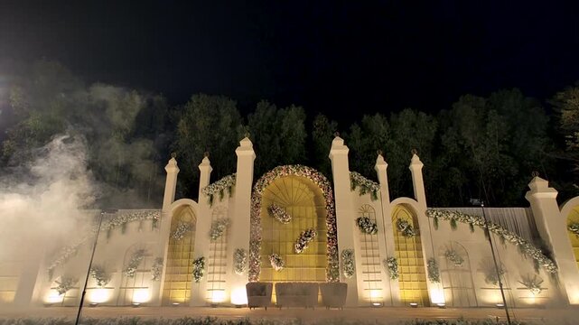 Cinematic tilt view of luxury wedding reception stage with dry fog and floral decor. Ideal for wedding films, event promos, romantic storytelling, and celebration visuals.