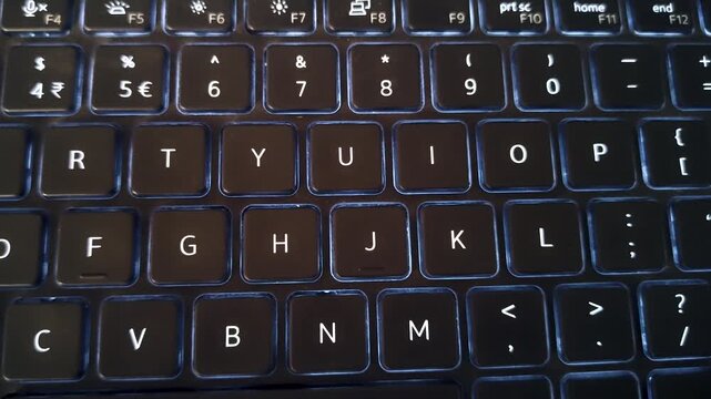 Close-up of laptop keyboard in low light. Ideal for coding, remote work, cybersecurity, typing concepts, digital workflow, and technology background visuals.