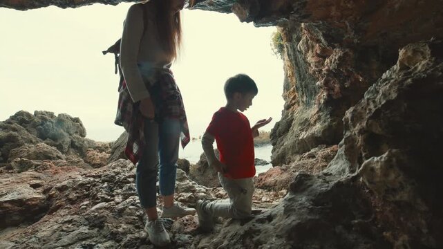 Mother and son exploring a rocky sea cave together