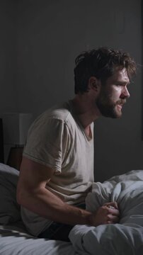 Man sitting in bed at night yelling from insomnia and distress, vertical shot