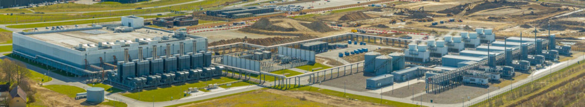 Panorama of a large scale data center facility under development with advanced power infrastructure, cooling systems, backup units. Expansion of high performance computing infrastructure.