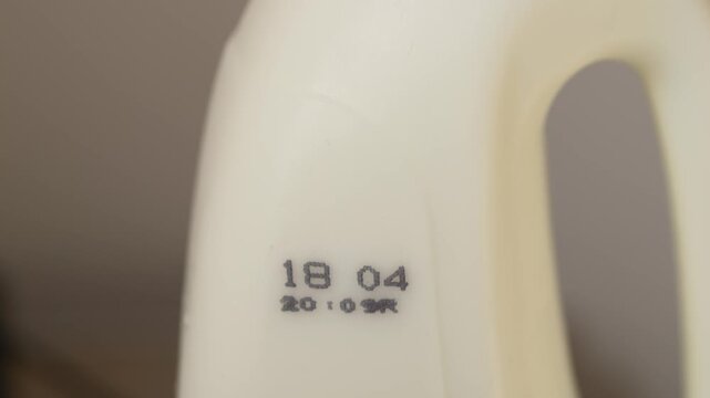 Minimal shot of milk container showing expiry date, representing food safety, refrigeration and monitoring product shelf life for health protection.Close up of milk bottle with visible date marking