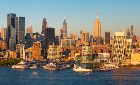 Midtown Manhattan skyline at sunset. Aerial wide-angle view of skyscrapers, the Hudson River waterfront and Chelsea piers. New York City, USA