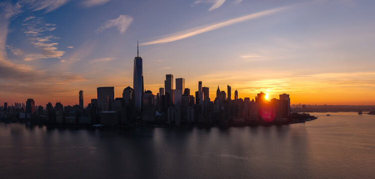 Aerial view of dawn and Lower Manhattan skyline over the Hudson River, New York City. Skyscrapers and urban waterfront at sunrise