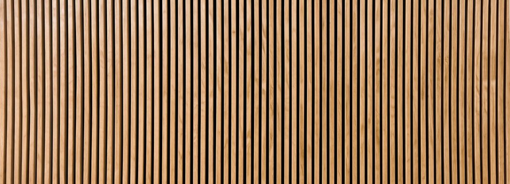 Close-up of a wooden panel with vertical slats in alternating light and dark tones, creating a striped pattern.