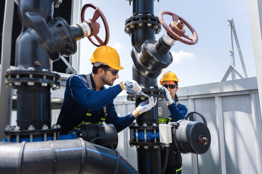Technicians in safety gear performing routine inspection and maintenance on a mechanical plumbing system, Professional maintenance team working with a wrench to fix heavy duty water or gas pipes