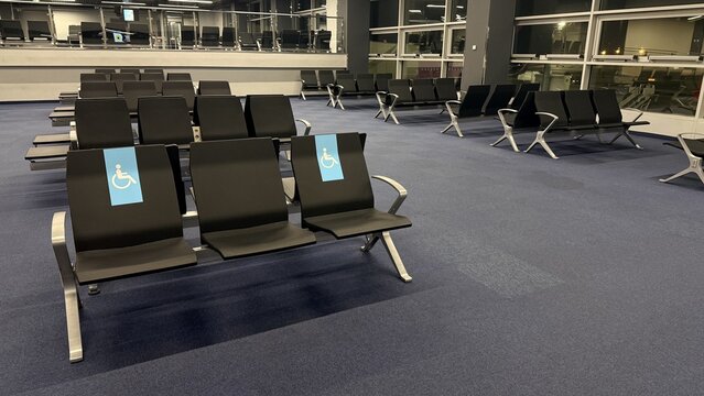 Empty airport waiting area with rows of black seats and wheelchair access signs, quiet late night atmosphere, travel and transit concept