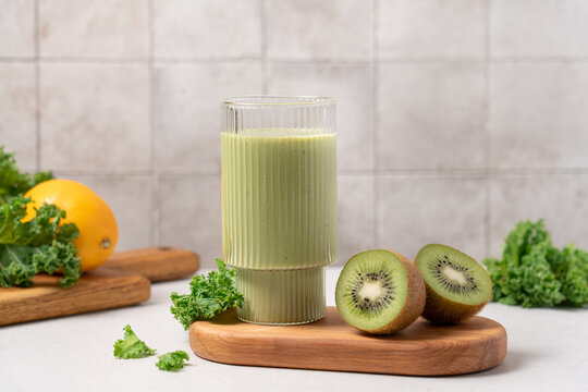 Green kale and kiwi smoothie in glass on light table with kitchen background and copy space, healthy eating and clean nutrition concept