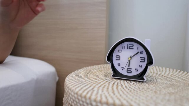 Person Reaching Out to Place Alarm Clock on Bedside Table