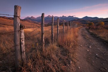 Fototapeta premium Golden hour landscape in southwest Colorado: rustic fence, warm dawn light, and distant alpine peaks