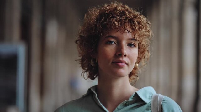 Portrait of young woman with curly red hair smiling with relaxed expression
