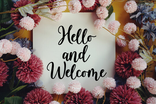 Hello and Welcome text with flower decoration on wooden background
