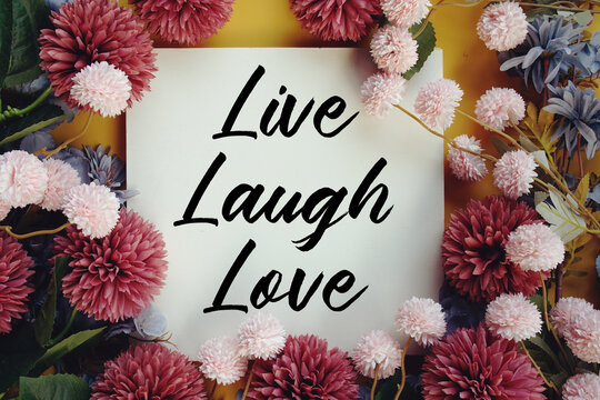 Live Laugh Love text with flower decoration on wooden background