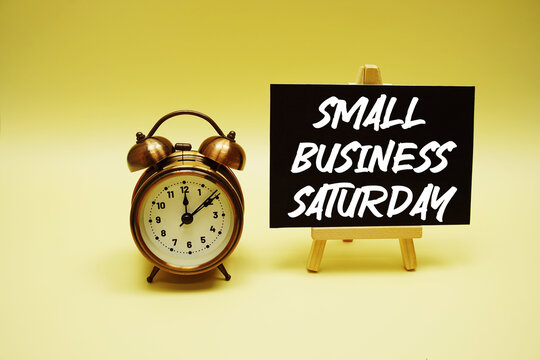 Small Business Saturday text message and alarm clock on yellow background