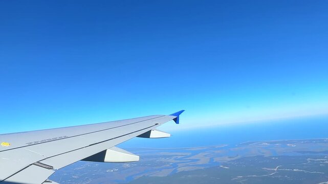 View from an airplane flying over a detailed urban landscape with a clear blue sky. Perfect for travel and aviation content.