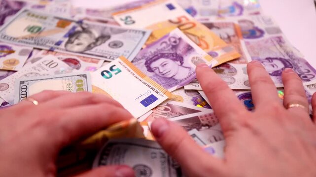 Woman's hands on a pile of money of different currencies