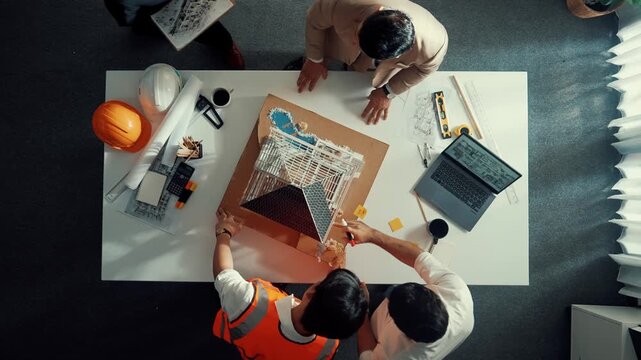 Top down aerial view of smart architect engineer team inspect house model while manager hold blueprint and asking about building construction. Group of diverse engineer working together. Alimentation.