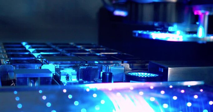 A close up view of automated machinery inserting components onto a circuit board during the manufacturing process. Robotic assembling microchip. Closeup shot.