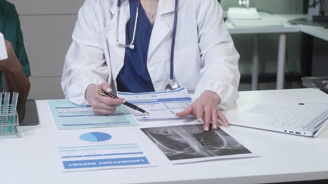 Doctor reviewing medical reports and x-ray at clinic desk