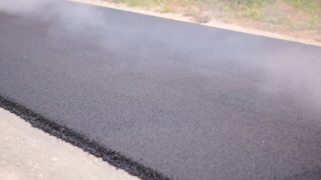 The road recycling machine is laying asphalt on the road, Pavement In-Place Recycling, Hot In-Place Recycling, Asphalt Hot Mix In-Place Recycling: Action Shot of Road Repair with Blurred Safety Cone