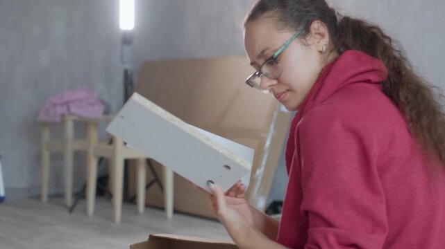 Woman Reviewing Panel Diagrams Carefully. Woman Inspecting Connector Details With Concentration. Woman Thoroughly Analyzing Connector Diagrams While Wearing Glasses During Do It Yourself Project