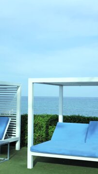 White Cabana With Bright Blue Cushions Overlooking Calm Ocean, Neat Hedge And Minimalist Poolside Setup, Modern Resort Detail Shot Ideal For Hospitality And Lifestyle Content