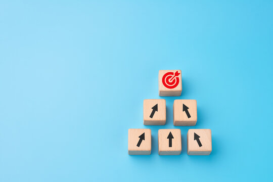 Goal achievement concept with wooden cube pyramid and target arrow