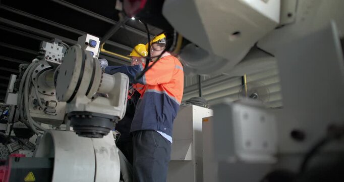 Robotic technicians use clamp meter to measure current within robotic arm. Troubleshooting process, aimed at diagnosing electrical issues, shorts, overloads, inefficiencies in electrical system.
