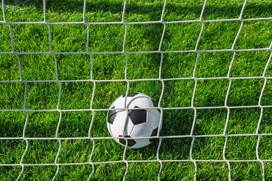 A soccer ball in the green fresh grass on the stadium.