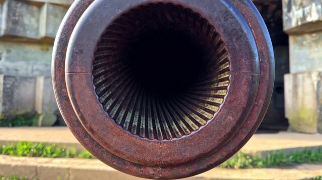 Macro shot dolly in rifled barrel of preserved WWII naval gun at Longues-sur-Mer battery revealing spiral grooves and rust texture