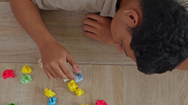 Overhead shot of person systematically lining up crumpled colorful paper balls on wood floor